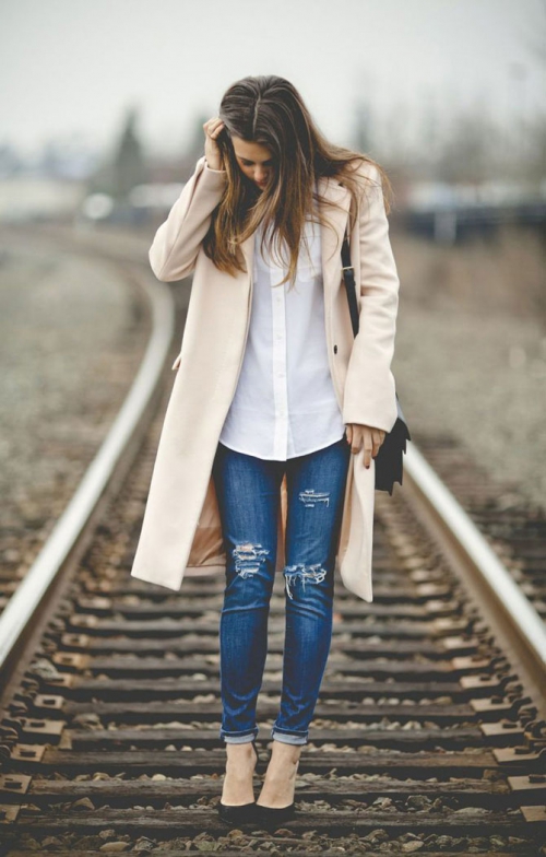 Девушка в пальто и рваных джинсах